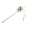 Close-up of a green floral hairpin with pearl tassels worn in dark hair