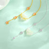Gold and silver tone necklaces with white jade fox pendants and pink flower charms on a light green background