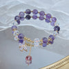 Close up of a purple glass beaded bracelet with a butterfly charm on a mirror surface
