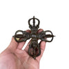 Hand holding an antique copper cross vajra with four prongs