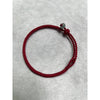 Close-up of a thin red woven bracelet with a small green jade bead and a fixed knot closure