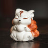 White ceramic nine-tailed fox figurine sitting on a dark surface