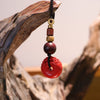 Red cinnabar keychain with carved Pixiu and peace buckle hanging from wood