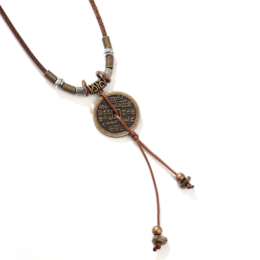 Close up of a bronze colored coin pendant on a brown cord necklace