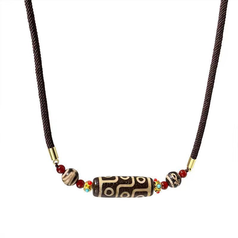 Close-up of a nine-eye dzi bead necklace worn against the collarbone.