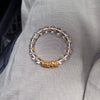 Close up of a clear crystal bracelet with a gold coiled wire accent on a wrist