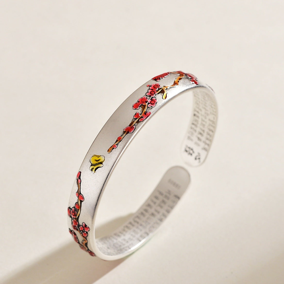 Silver tone open cuff bracelet with red enamel plum blossoms and Heart Sutra engraving inside