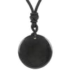 Close up of a black round stone pendant on a knotted black cord against a white background