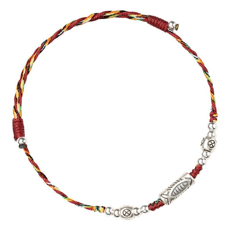 Close up of a colorful braided cord bracelet with silver colored charms on a white background