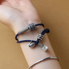 Blue woven rope bracelet with silver-tone Tibetan beads on a wrist
