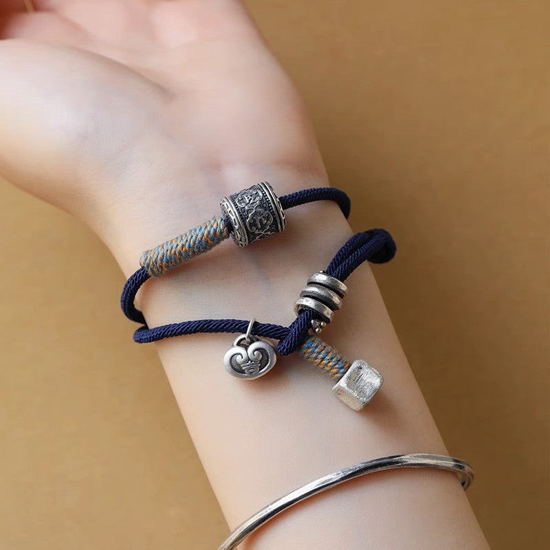 Blue woven rope bracelet with silver-tone Tibetan beads on a wrist