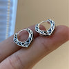 Close up view of small geometric copper hoop earrings with black lines held on fingers