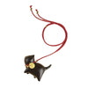 A hand holding a dark wood carved cat car hanging decoration with a red cord