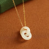 Gold tone necklace with interlocking white rings pendant on a green background