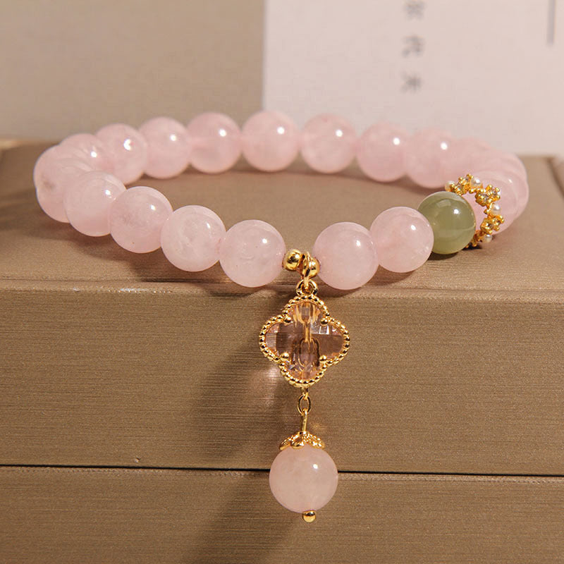Pink crystal beaded bracelet with a gold-tone four leaf clover charm