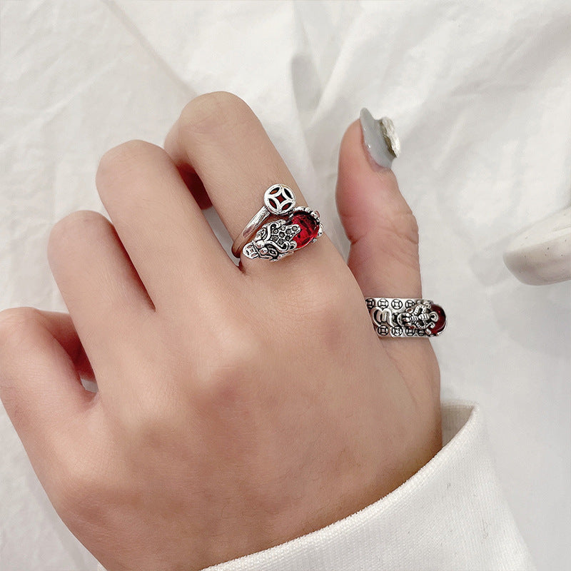 Hand wearing a vintage silver ring with a red stone and Pixiu design