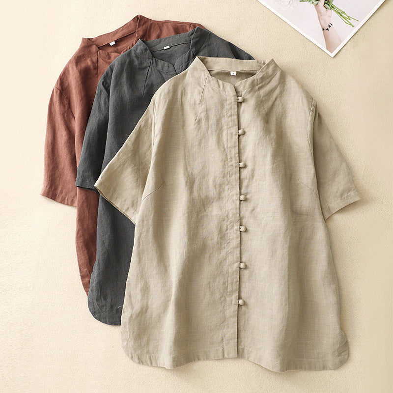 Three folded cotton linen shirts in beige, grey and brown showing the stand collar and button detail