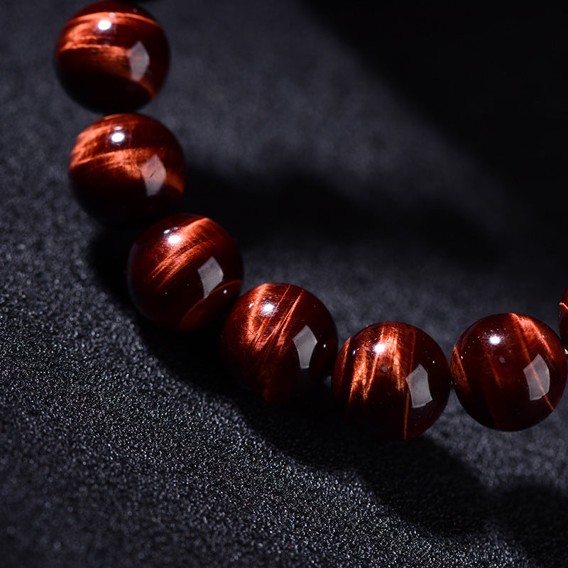Close-up view of a natural red tiger eye bead bracelet showing the lightning pattern texture