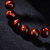 Close-up view of a natural red tiger eye bead bracelet showing the lightning pattern texture
