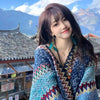 Woman wearing a multi-colored knitted Tibetan shawl with tassels in an outdoor setting
