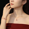 Model wearing a rose gold horse charm bracelet and matching necklace with red beads
