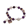 Close up of a hand wearing a purple beaded bracelet with a gold flower charm