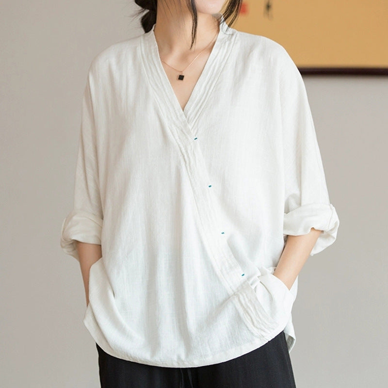 Woman wearing a white long sleeve V-neck shirt with rolled up sleeves