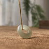 Close up of a smooth pale jade donut pendant on a gold chain