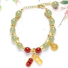 Double strand bracelet with light green jade beads and a gold peanut charm on a white background