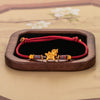 Gold-tone flying horse charm on a red string bracelet with colorful spacers