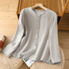 A light grey cotton linen long sleeve shirt with button front hanging on a wooden hanger