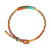 Close up of a multicolor woven bracelet with gold tone ends on a wrist