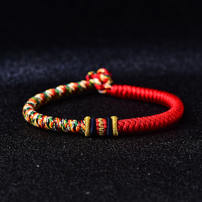 Close-up of a red and multicolored braided bracelet with silver accents on a black background