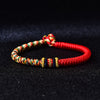Close-up of a red and multicolored braided bracelet with silver accents on a black background