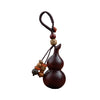 A dark wooden gourd keychain hanging against a white background