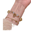 Close up of a wrist wearing a gold tone bracelet with yellow citrine and white moonstone beads plus a butterfly charm