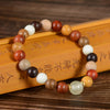 A close-up view of a multi-tone wooden bead bracelet resting on a wooden surface