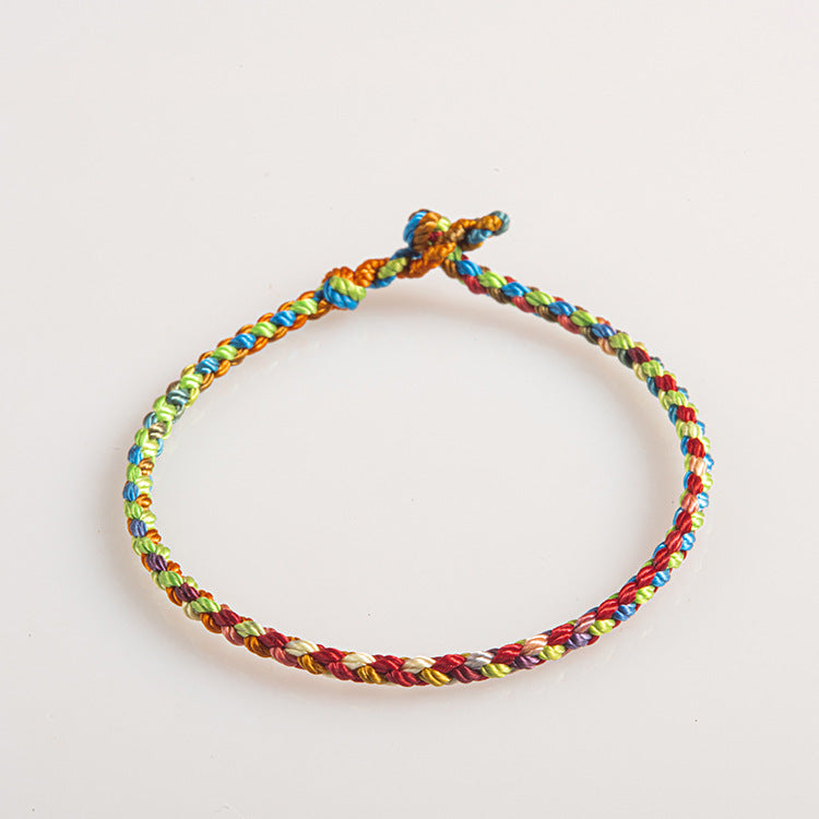 Close-up view of a multicolored braided string bracelet with an adjustable knot on a white background