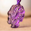 Close up view of a carved purple amethyst pendant in the shape of a fox head