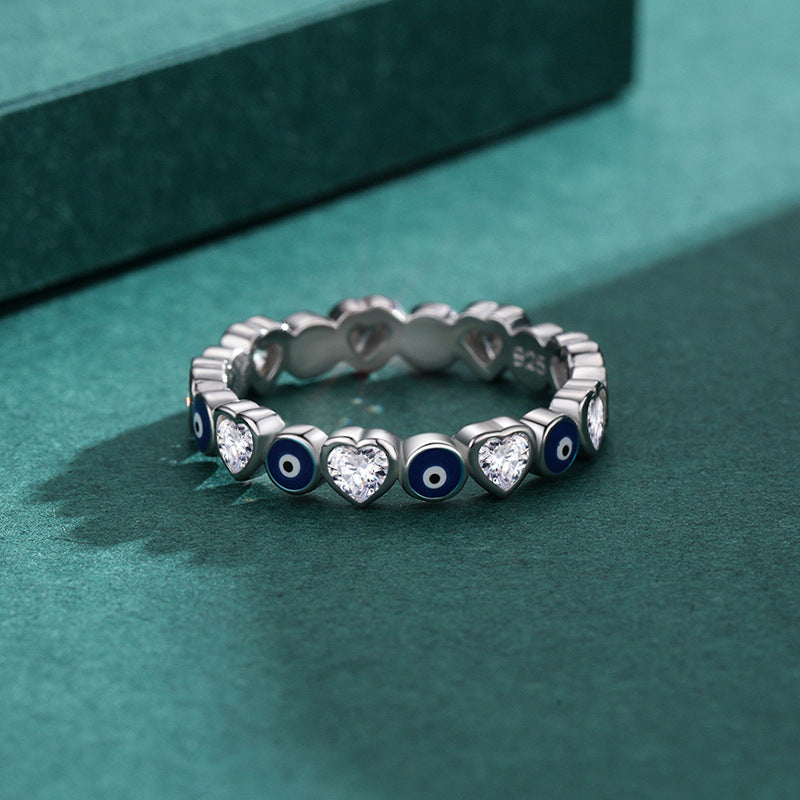 Close up of a woman's hand wearing a silver ring with blue evil eyes and hearts
