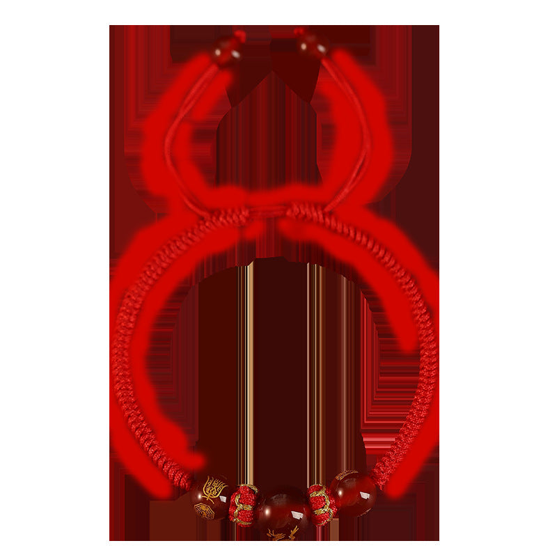Close up of a red braided bracelet with a red agate bead featuring a gold zodiac charm