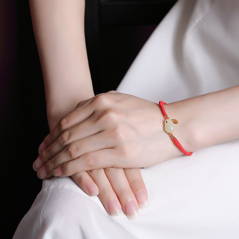 Hand-woven red string bracelet with a white jade rabbit charm and gold plated ears