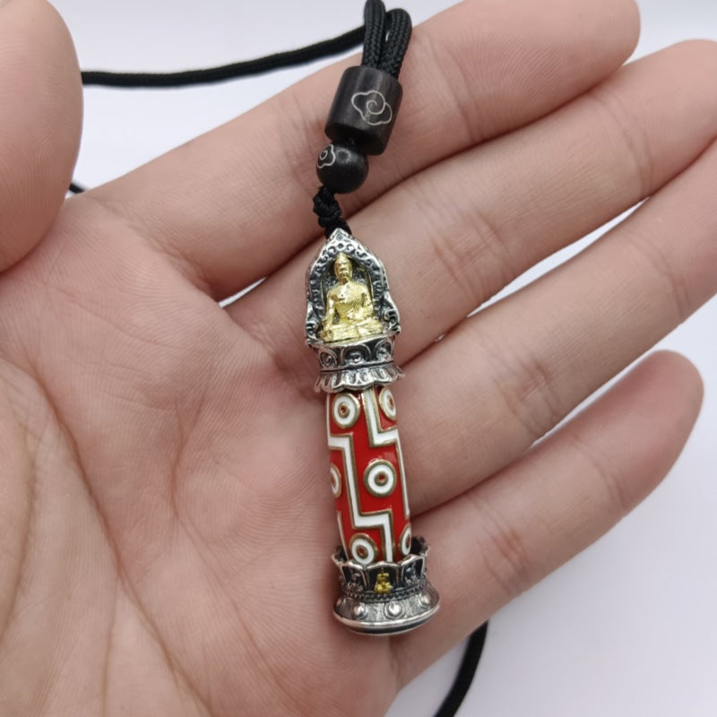 Close-up of a red and white nine-eye Dzi bead pendant with a gold Buddha figure on top