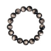 A wrist wearing a bracelet made of black beads with a silver metallic sheen.