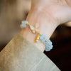 Close-up of a light blue beaded bracelet with a gold butterfly charm on a wrist
