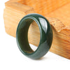 Polished dark green geometric ring resting on a wooden block
