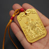 Hand holding a rectangular gold-tone metal pendant featuring a seated scholar figure