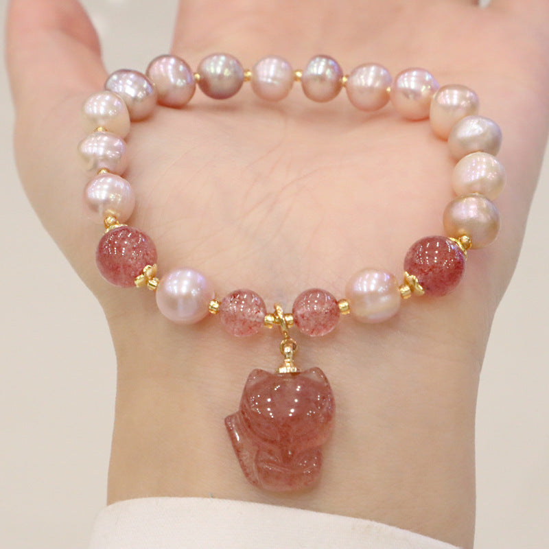 Wrist wearing a pink pearl and strawberry quartz bracelet with a fox pendant