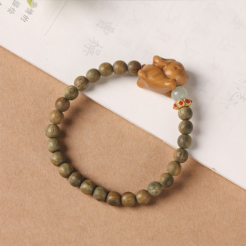 Green wooden beaded bracelet with a carved rabbit charm worn on a wrist