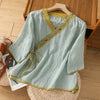Light green embroidered cotton linen top on a wooden hanger